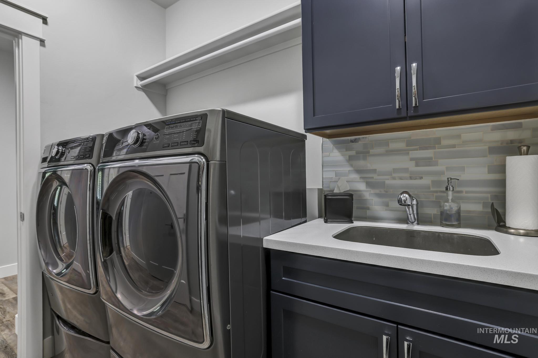 1937 Tamarack Loop Twin Falls, ID 83301 - Photo 30 of 50 Laundry room featuring a built-in utility sink with a chrome faucet, dark cabinetry, and a tile backsplash