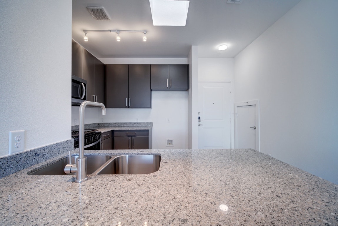 13130 Pond Springs Road, Unit 3212 Austin, TX 78750 - Photo 14 of 33 a kitchen with stainless steel appliances granite countertop a sink a stove and a refrigerator