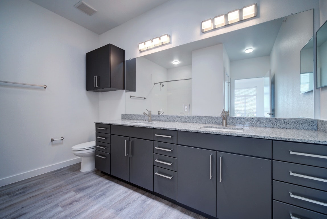 13130 Pond Springs Road, Unit 3212 Austin, TX 78750 - Photo 24 of 33 a bathroom with a granite countertop sink a toilet and a mirror