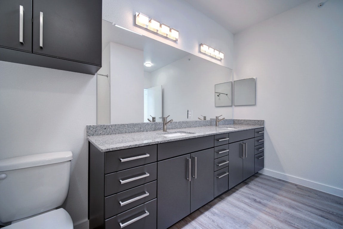 13130 Pond Springs Road, Unit 3212 Austin, TX 78750 - Photo 26 of 33 a bathroom with a granite countertop toilet a sink and a mirror