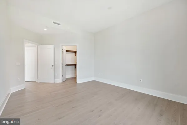 a view of an empty room with wooden floor and bathroom