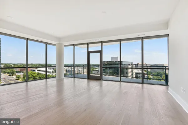 a view of an empty room with wooden floor and city view