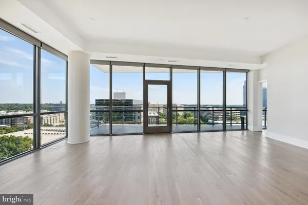 an empty room with wooden floor and floor to ceiling window