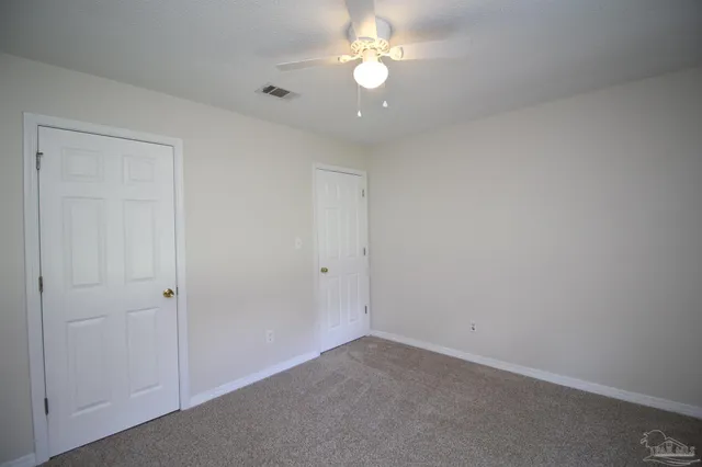 an empty room with a ceiling fan and a window