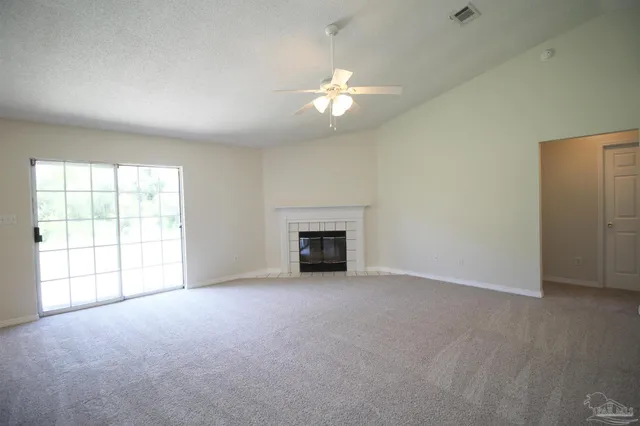 an empty room with chandelier fan and windows