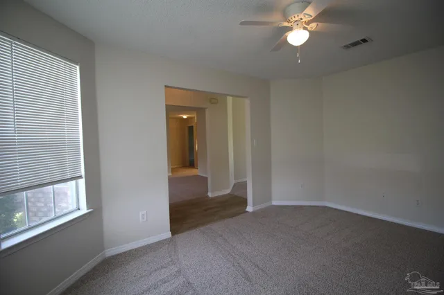an empty room with windows and fan