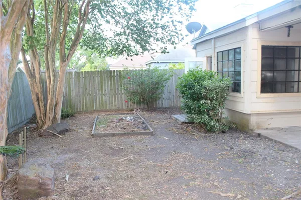 a view of a backyard with large trees and wooden fence