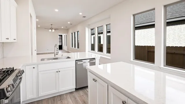 a large white kitchen with a sink large window and stainless steel appliances