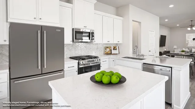 a kitchen with stainless steel appliances a sink a stove a microwave a refrigerator a stove and white cabinets