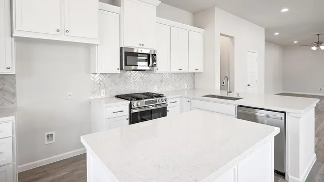 a kitchen with stainless steel appliances a sink stove and white cabinets