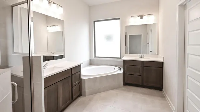 a bathroom with a double vanity sink mirror and bathtub