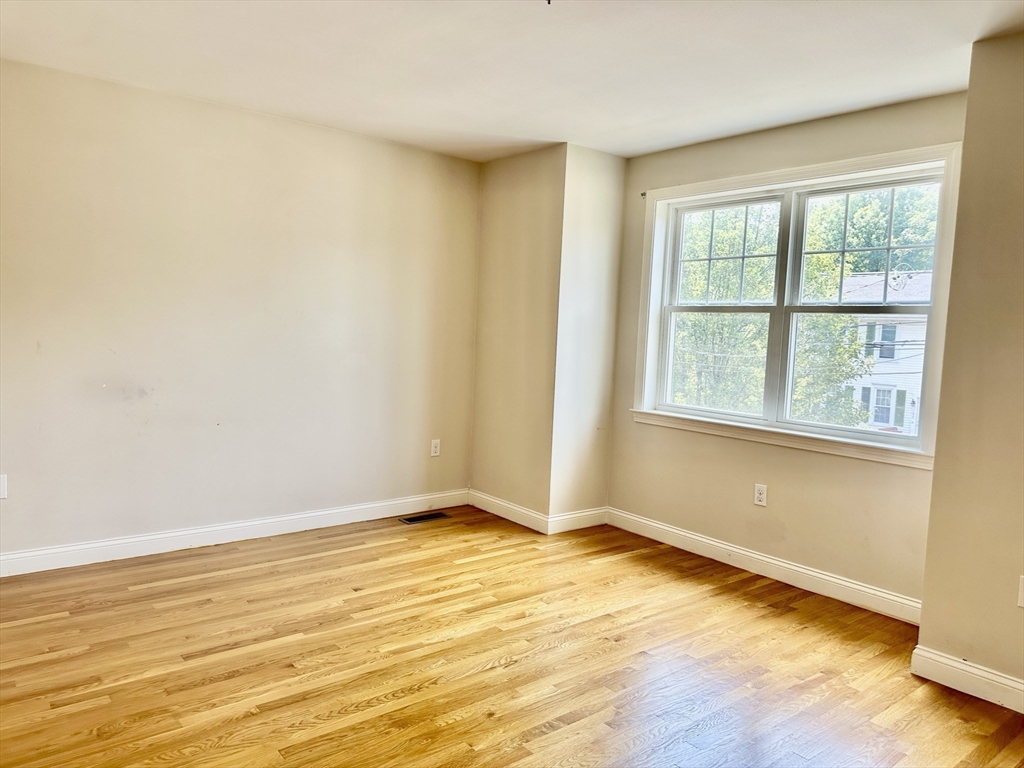 183 Summer Street, Unit 183 Watertown, MA 02472 - Photo 7 of 12 a view of an empty room with wooden floor and a window