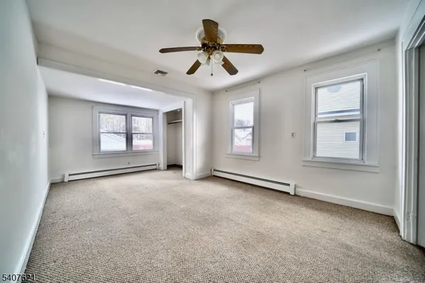 an empty room with windows and ceiling fan