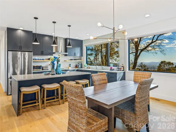 a living room with stainless steel appliances kitchen island granite countertop a table chairs and a refrigerator