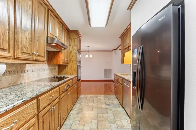 a kitchen with granite countertop a sink and a refrigerator