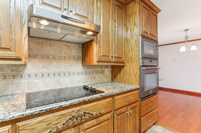 a kitchen with granite countertop stainless steel appliances a counter space and cabinets