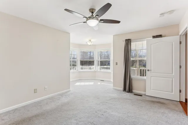 an empty room with chandelier fan and windows
