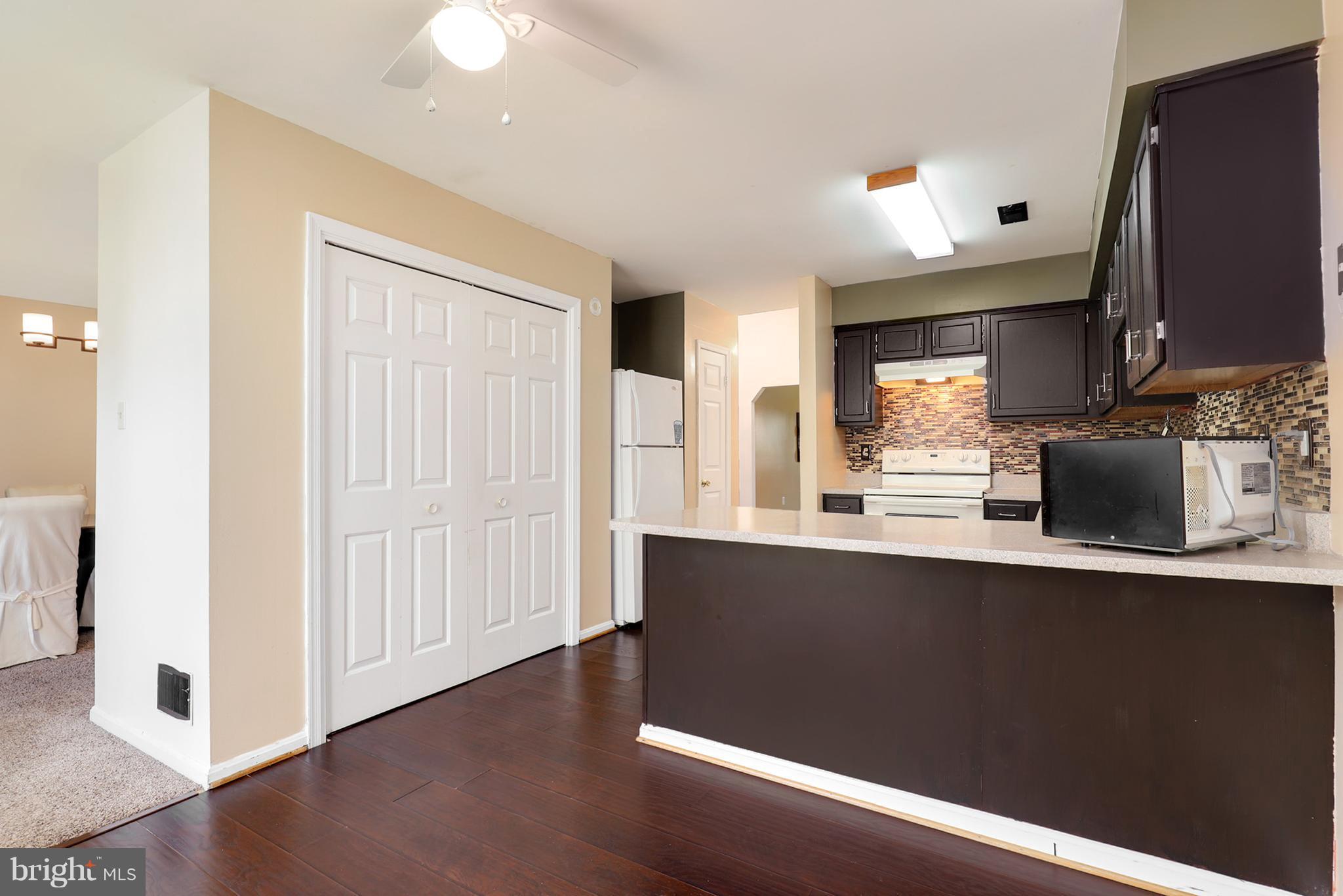 10604 Gator Court Clinton, MD 20735 - Photo 12 of 24 a kitchen with stainless steel appliances granite countertop a sink a stove a refrigerator a microwave oven with wooden floor and cabinets