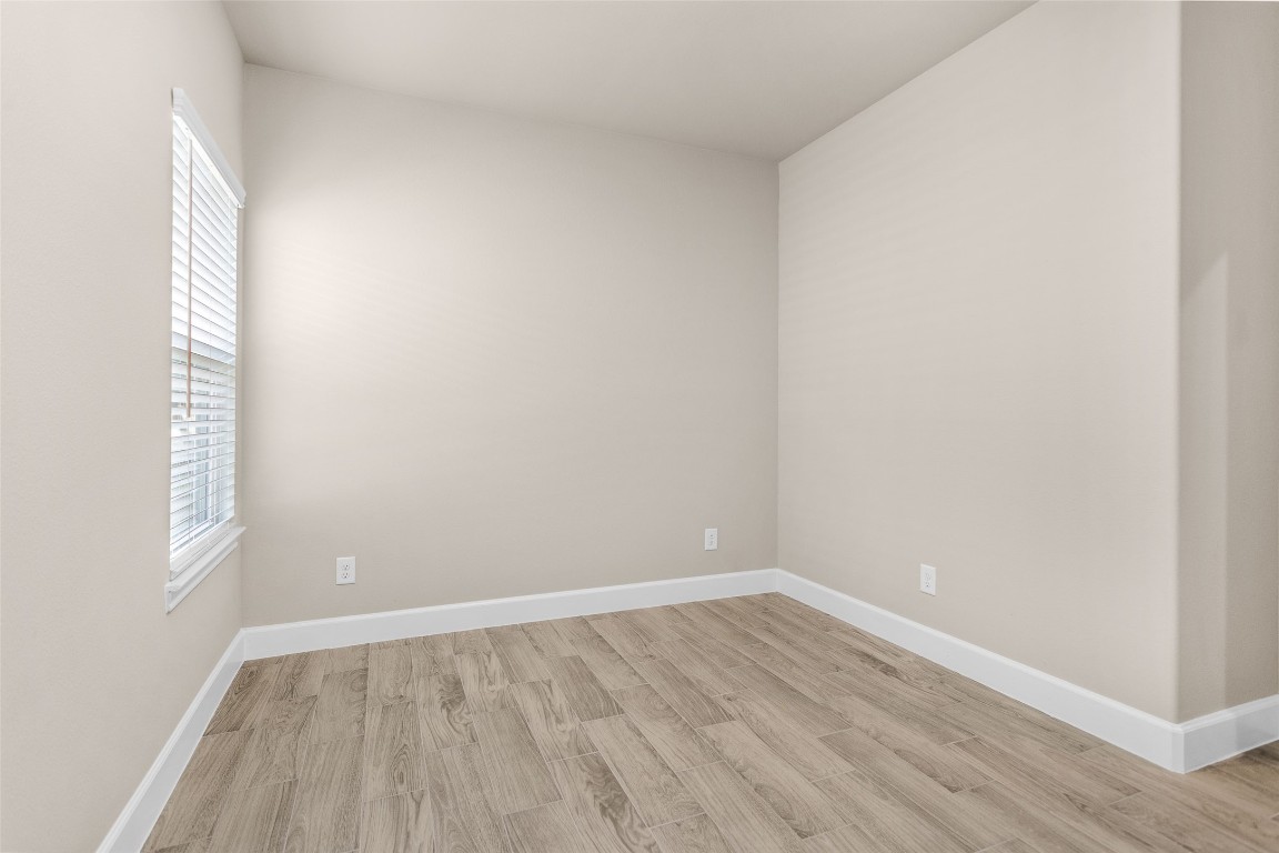 496 Golden Street, Unit A Willis, TX 77378 - Photo 11 of 26 a view of an empty room with wooden floor and a window