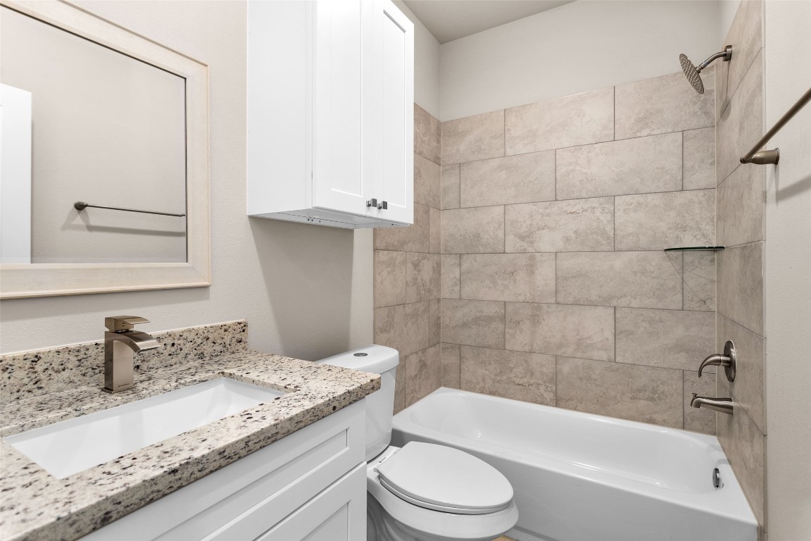 496 Golden Street, Unit A Willis, TX 77378 - Photo 13 of 26 a bathroom with a granite countertop bathtub shower sink vanity mirror and toilet