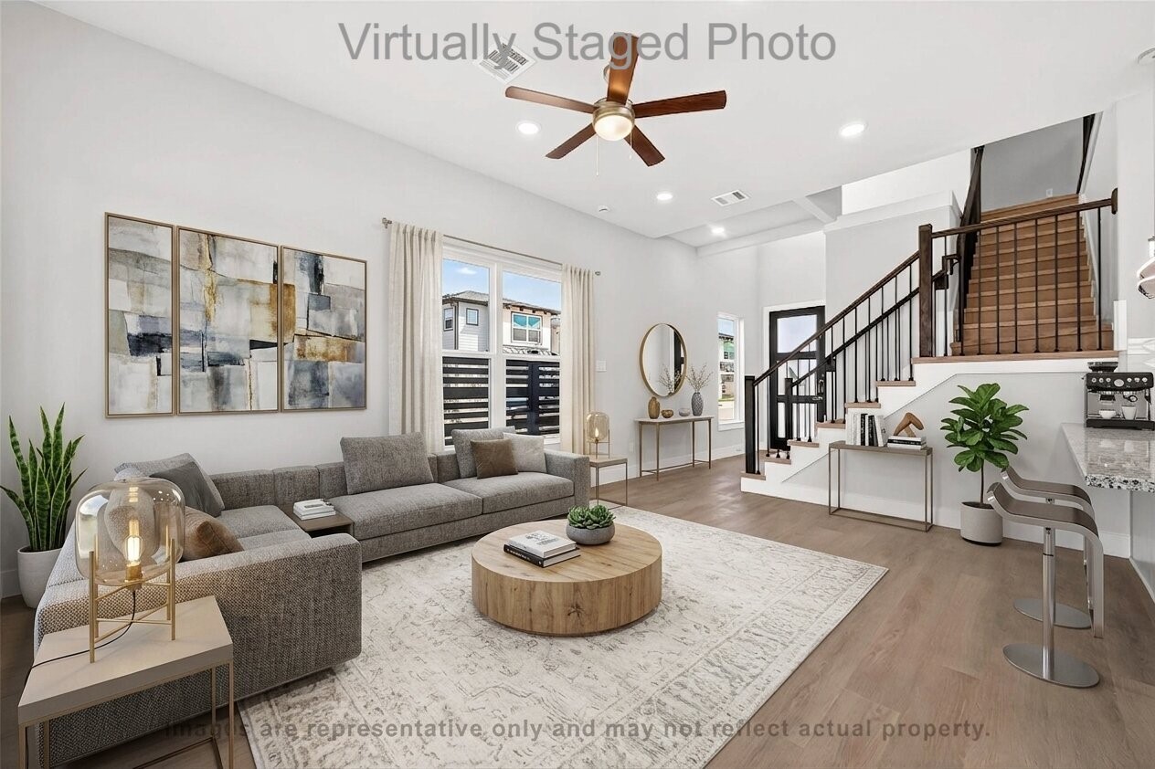 10719 Mason Road, Unit 39 Richmond, TX 77406 - Photo 7 of 50 Virtual Staging - Modern living room featuring a large gray sectional sofa, a round wooden coffee table, and an adjacent open staircase_