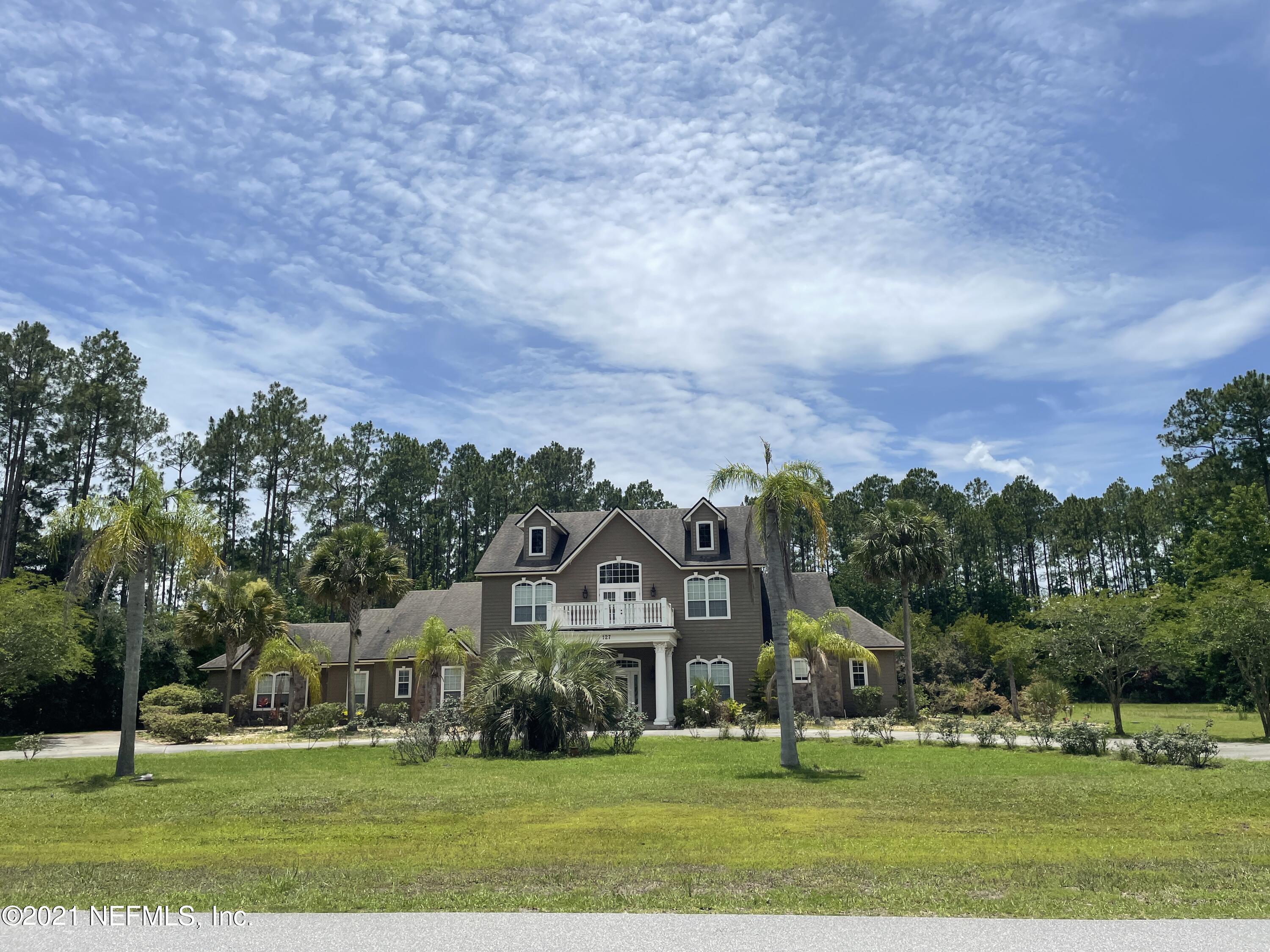 a view of a big house with a big yard and large trees