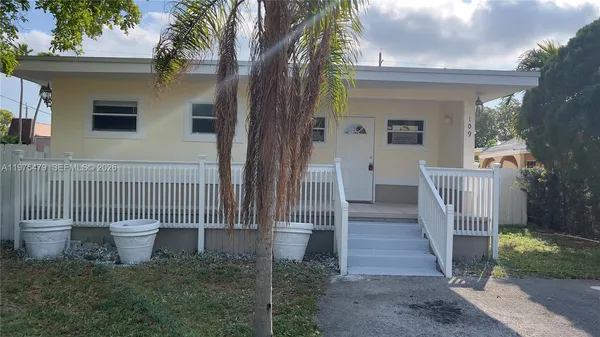 a view of a house with wooden fence next to a yard