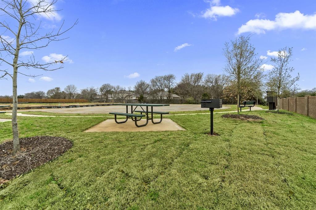 3344 Duncan Way Corinth, TX 76210 - Photo 36 of 38 Open green space featuring a picnic table on a concrete pad, a permanent grill, and mature trees