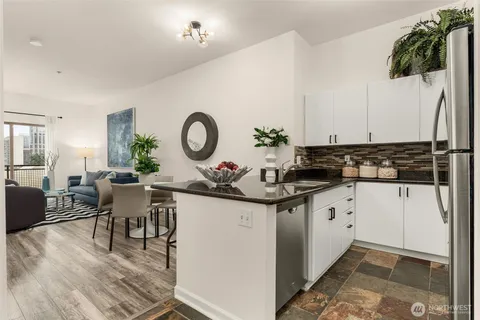 a kitchen with granite countertop a sink a stove a dining table and chairs