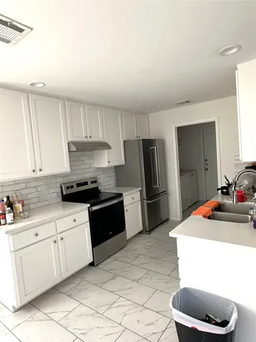 a kitchen with stainless steel appliances a sink a stove a refrigerator a counter space and cabinets