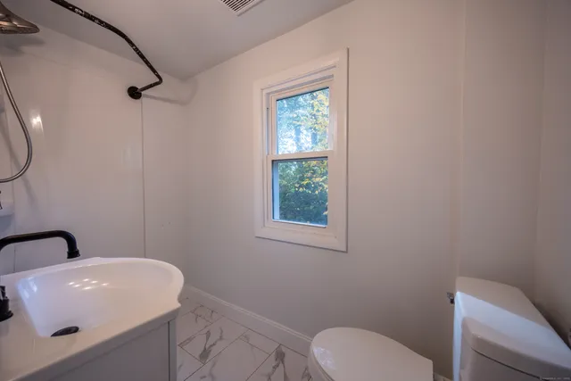 a bathroom with a toilet a sink and mirror
