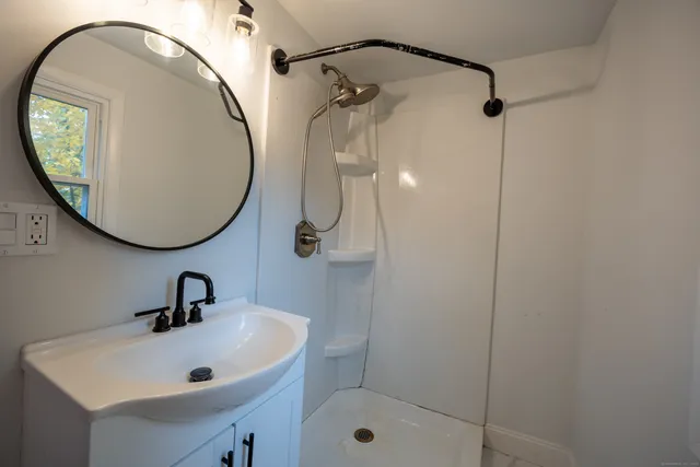 a bathroom with a sink a shower and a mirror