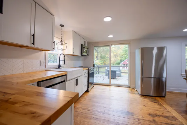 a kitchen with stainless steel appliances granite countertop a refrigerator a sink dishwasher a stove and white countertops with wooden floor