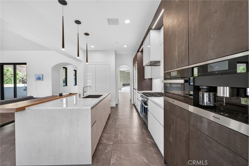 43754 De Luz Road Temecula, CA 92590 - Photo 42 of 74 a large kitchen with stainless steel appliances a large counter top a stove a chimney and a refrigerator