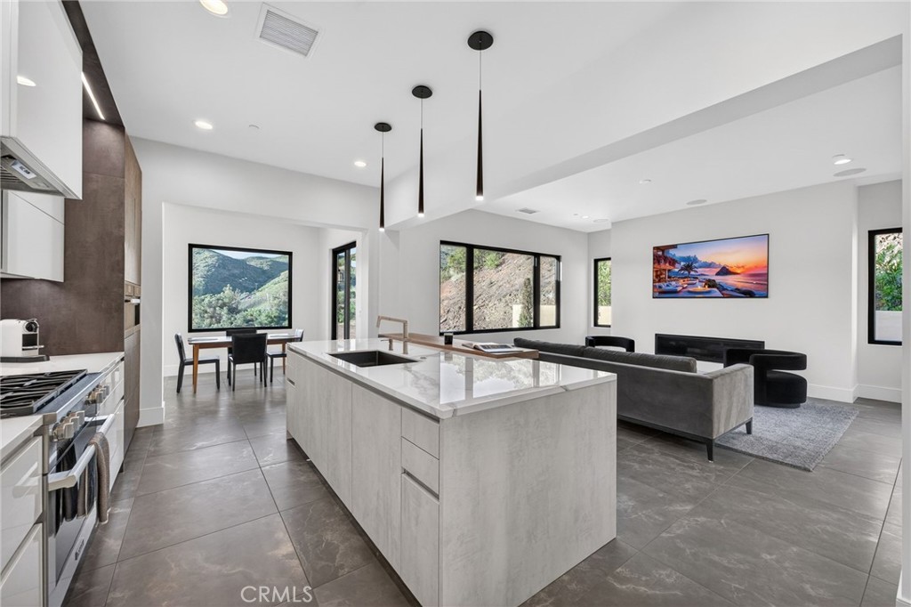 43754 De Luz Road Temecula, CA 92590 - Photo 46 of 74 a large kitchen with kitchen island a large counter top space a sink a stove and a chandelier