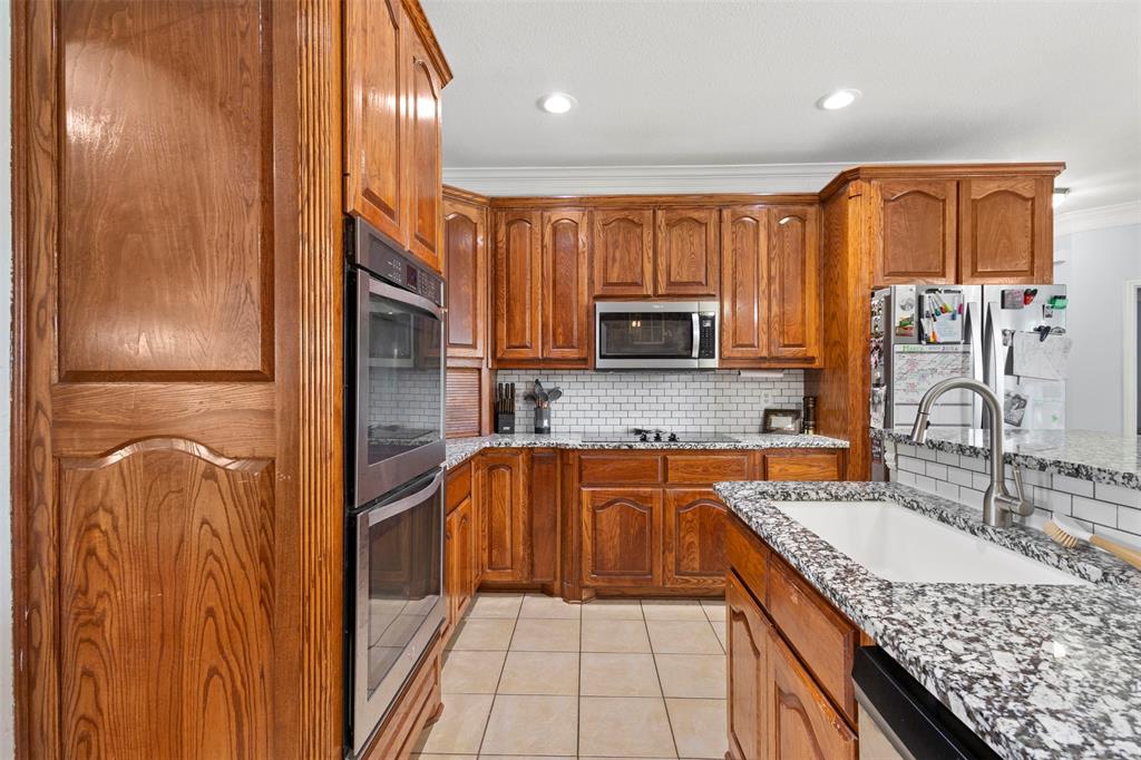 2000 Pin Oak Drive Kaufman, TX 75142 - Photo 14 of 40 a kitchen with stainless steel appliances granite countertop a sink and dishwasher a stove with wooden cabinets