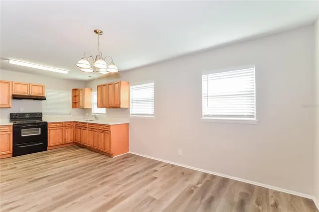 a large kitchen with a refrigerator a stove top oven a sink dishwasher and wooden floor