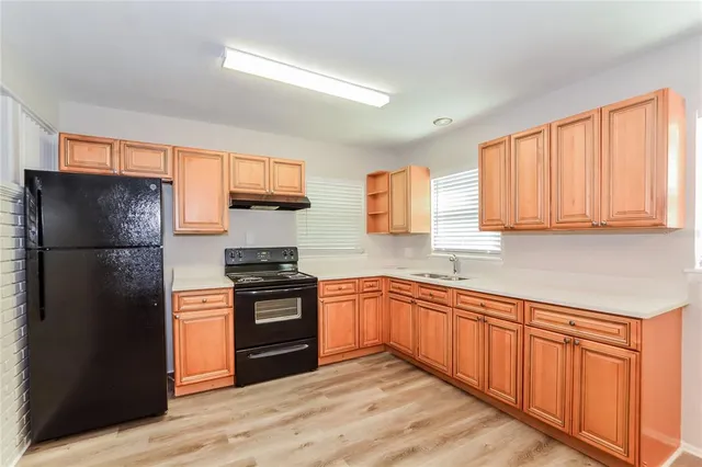 a kitchen with stainless steel appliances granite countertop a refrigerator stove top oven and granite countertops with wooden floor