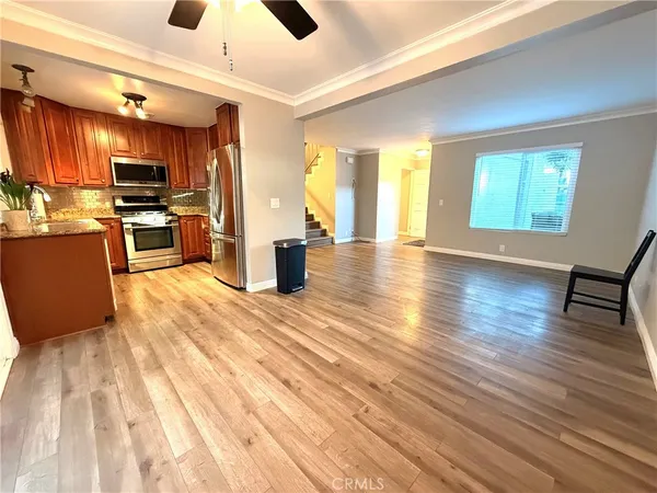 a kitchen with stainless steel appliances kitchen island granite countertop a refrigerator a sink dishwasher a stove and a dining table with wooden floor