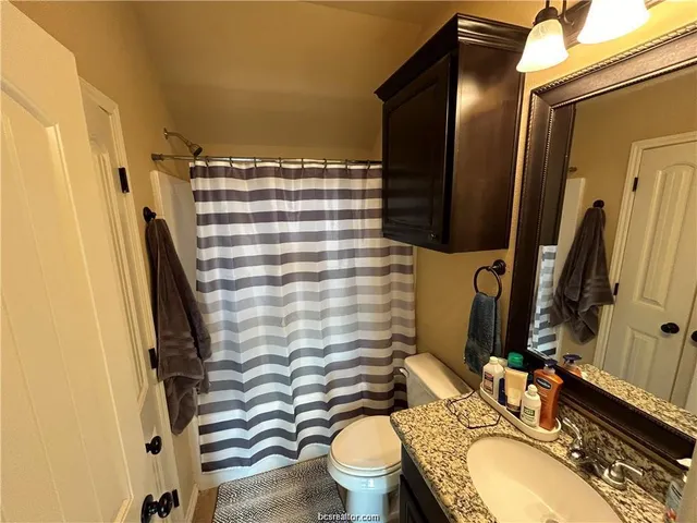 a bathroom with a granite countertop toilet sink and mirror