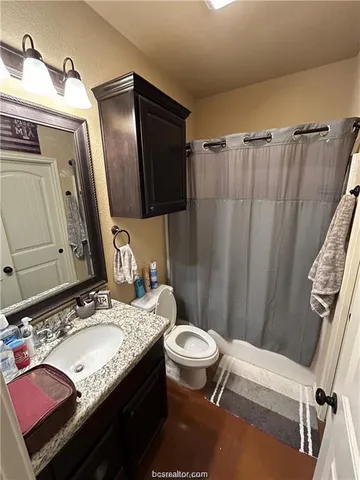 a bathroom with a granite countertop sink toilet and mirror