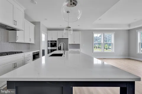 a large kitchen with stainless steel appliances a large counter top a stove a chimney a sink and a center island