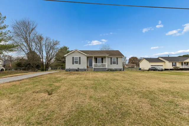 a front view of house with yard and trees in the background