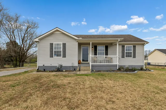 a front view of house with yard and trees in the background