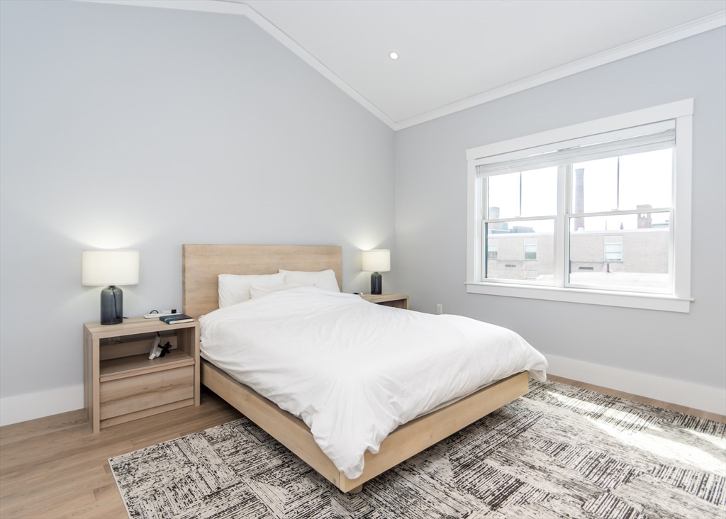 29 Cherry Street, Unit 2 Waltham, MA 02453 - Photo 13 of 32 a bedroom with a bed lamp and a window