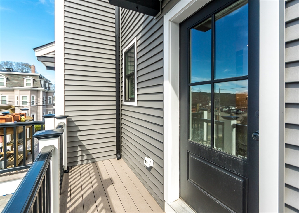 29 Cherry Street, Unit 2 Waltham, MA 02453 - Photo 29 of 32 a view of a balcony with wooden floor and iron stairs