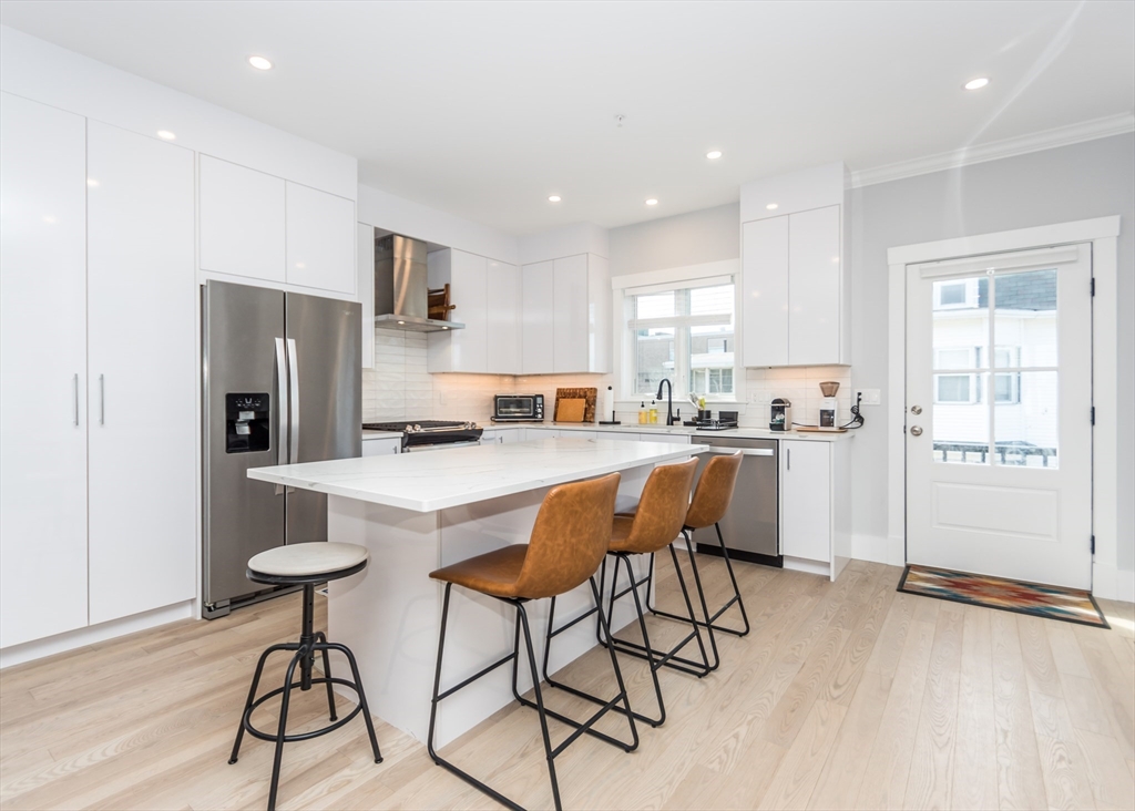 29 Cherry Street, Unit 2 Waltham, MA 02453 - Photo 5 of 32 a kitchen with stainless steel appliances kitchen island granite countertop a refrigerator and a stove top oven