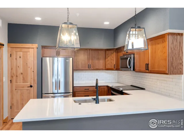 a kitchen with stainless steel appliances kitchen island granite countertop a refrigerator a stove and white cabinets