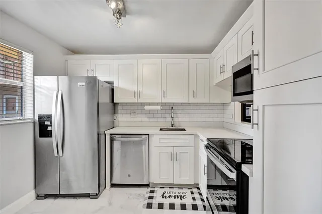a kitchen with stainless steel appliances a refrigerator sink and cabinets