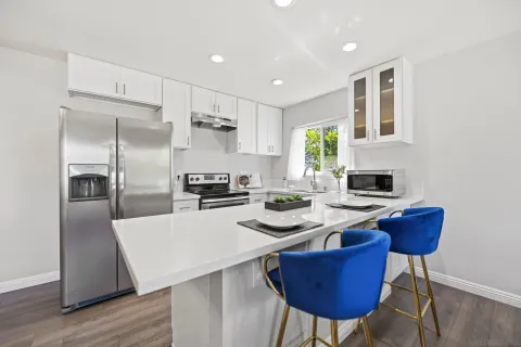 a kitchen with a refrigerator a stove a sink and a dining table with wooden floor